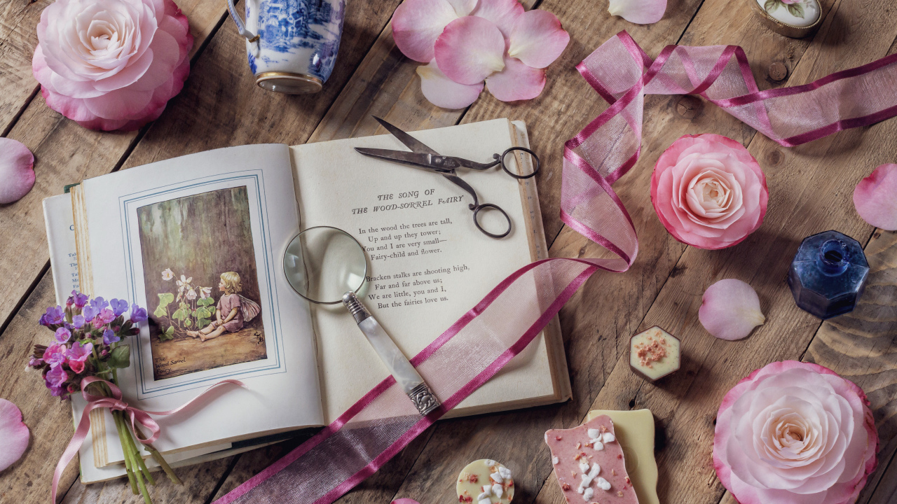 Старая книга на столе с увеличительным стеклом и искусственными цветами