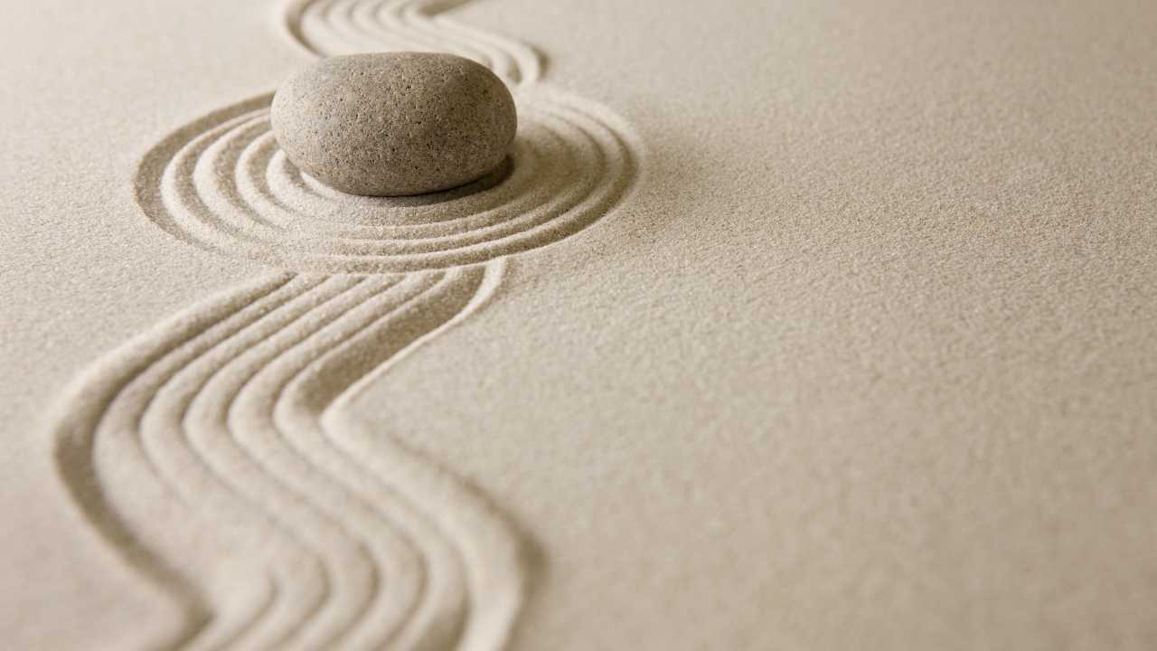 Камень лежит на рисунке на песке, дзен