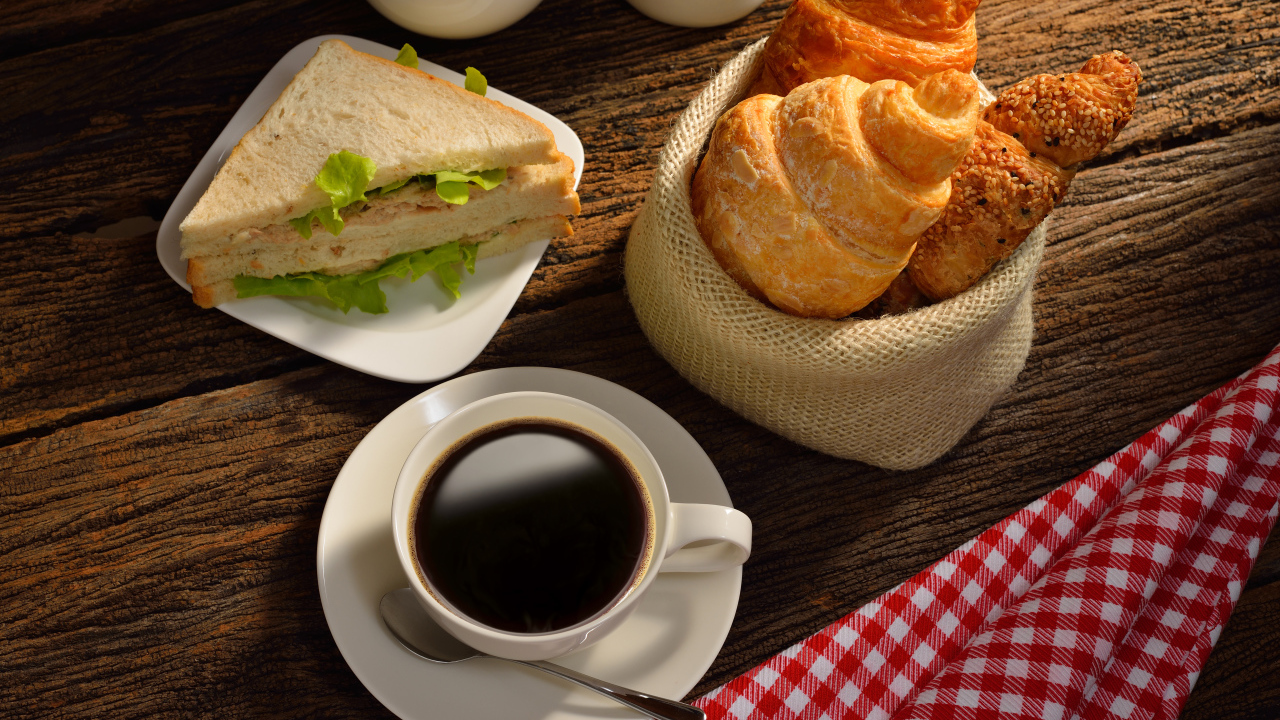 A cup of coffee with croissants and sandwiches for breakfast