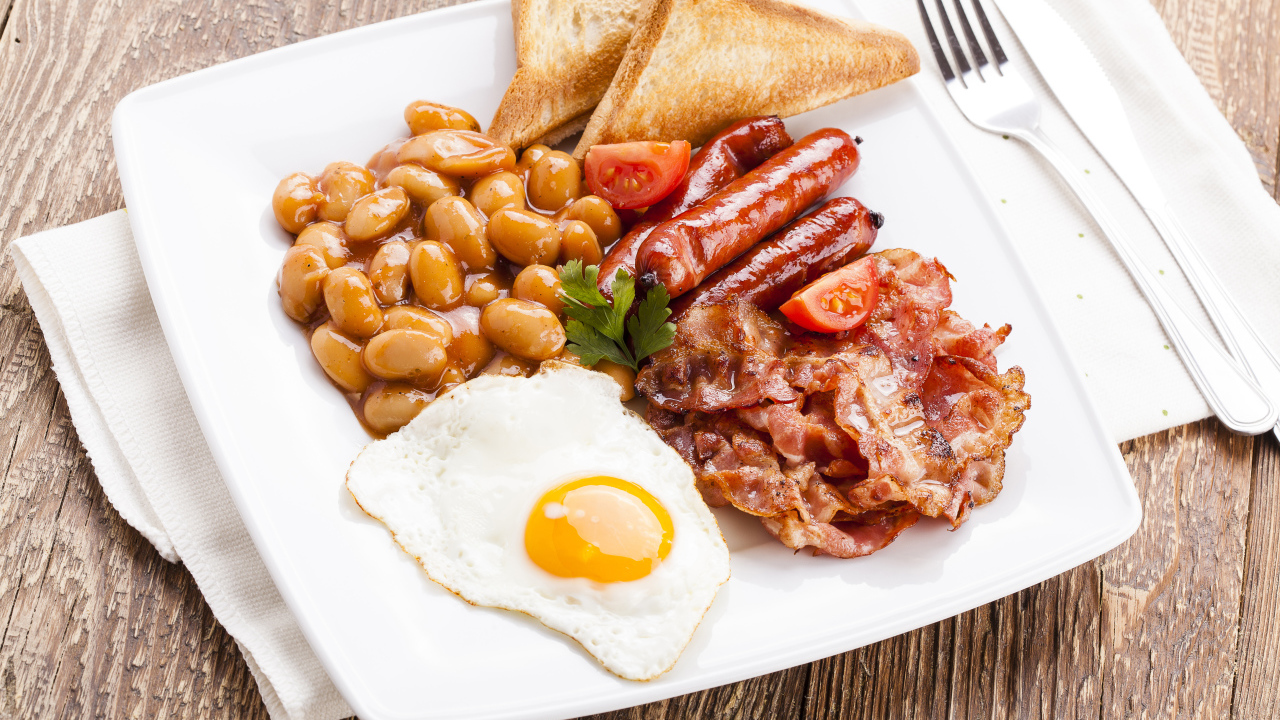 Бекон, яичница, фасоль и сосиски на тарелке к завтраку 