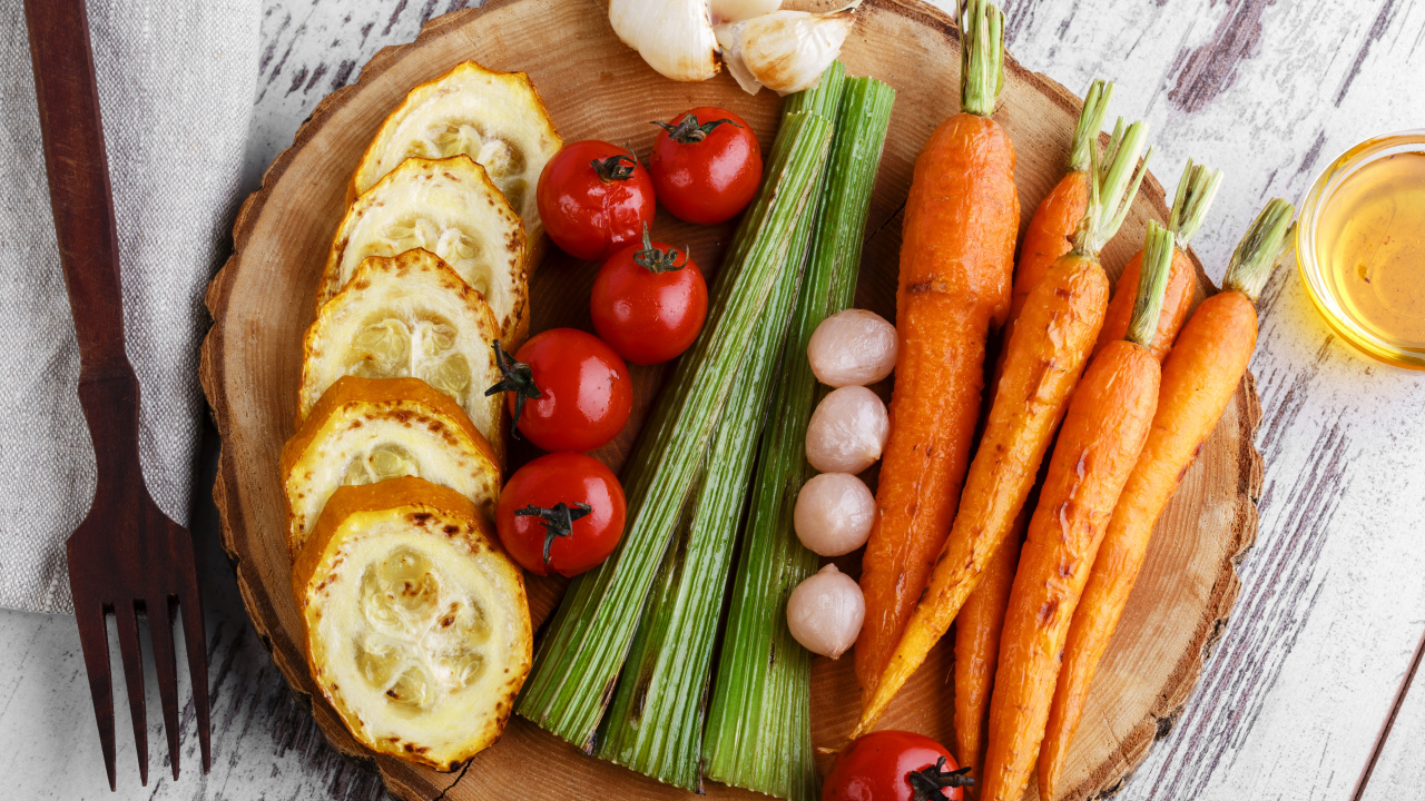 Печеные кабачки, помидоры, морковь, сельдерей и чеснок на разделочной доске