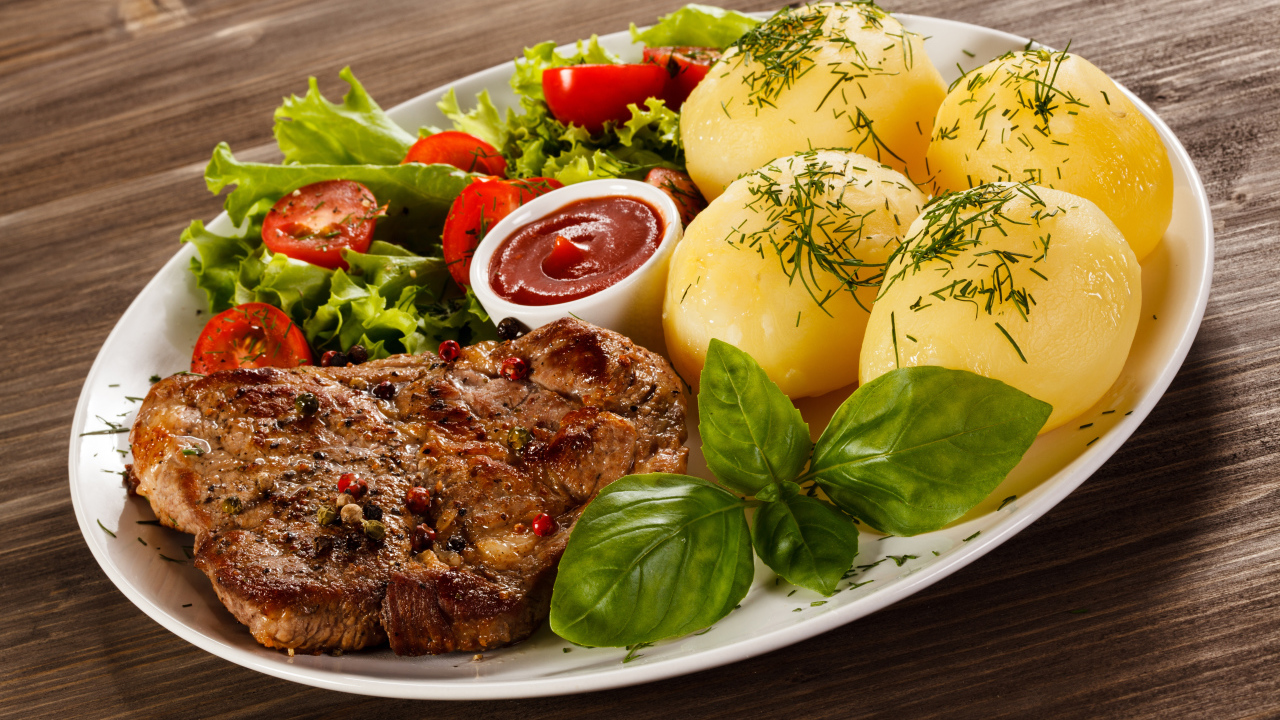 Вареный картофель с куском мяса и салатом на тарелке