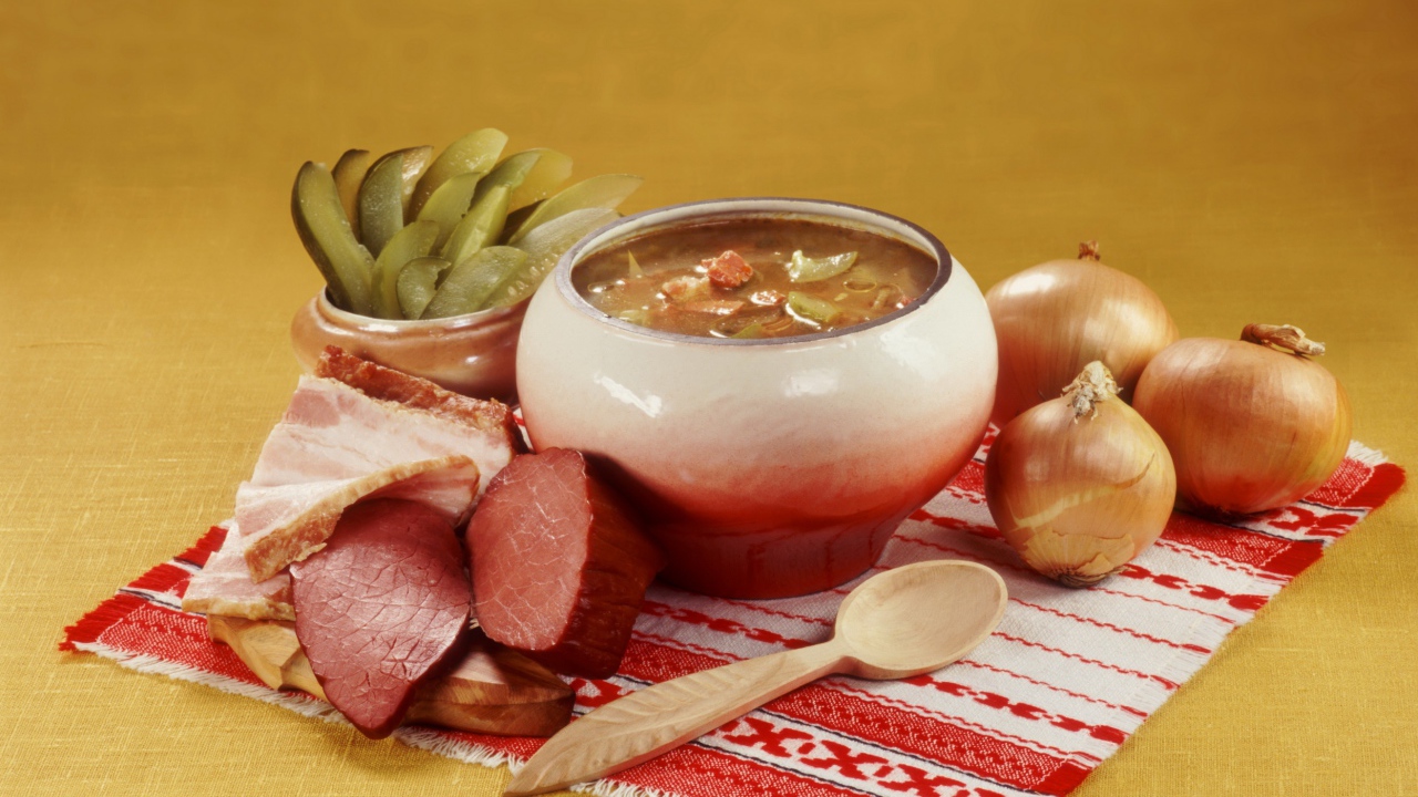 Борщ на столе с мясом, солеными огурцами и луком