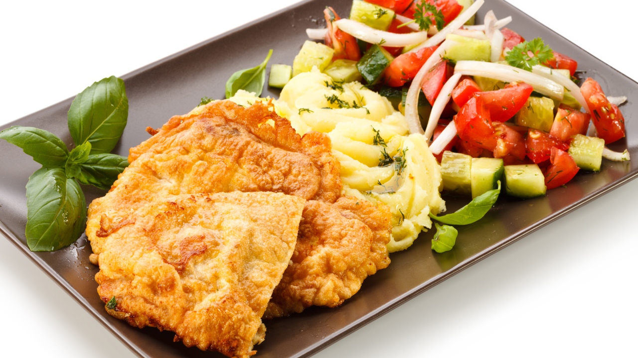 Отбивные с пюре и овощным салатом на тарелке