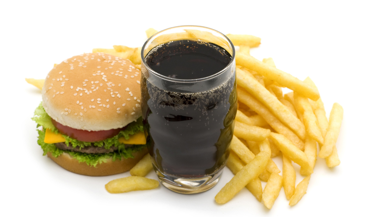 Кола в стакане на столе гамбургером и картофелем фри на белом фоне