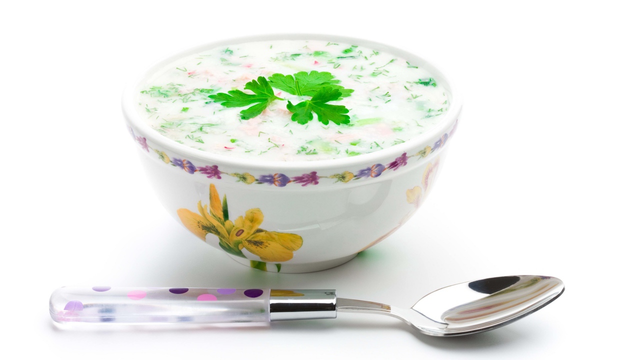 Аппетитная вкусная окрошка в тарелке на белом фоне с ложкой 