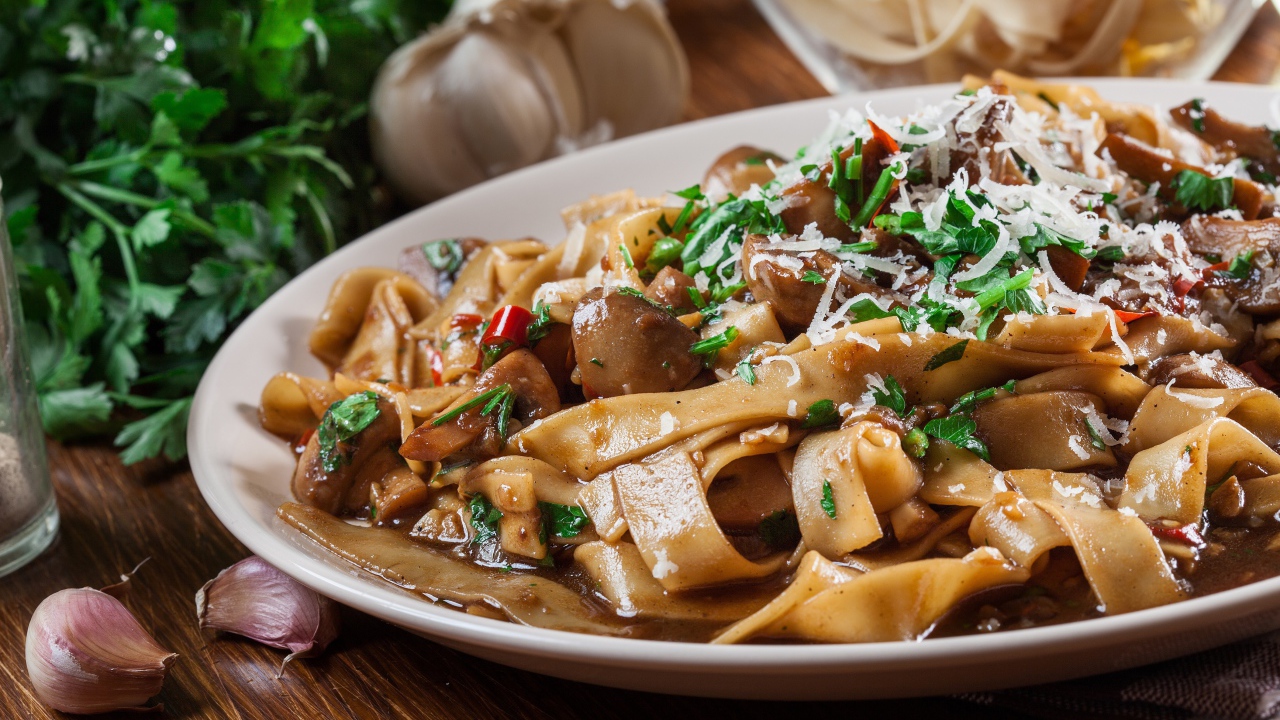 Паста с грибами, сыром и  зеленью на столе с чесноком 