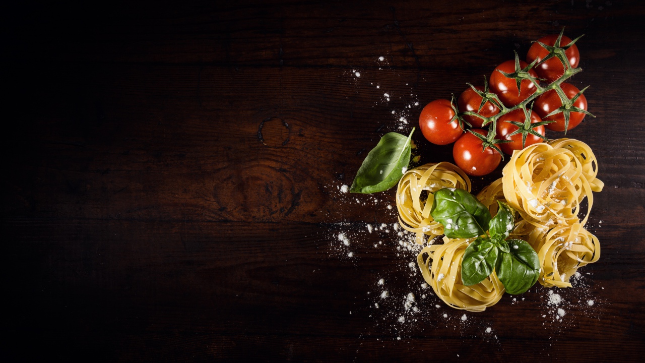 Паста с помидорами и листьями базилика на столе