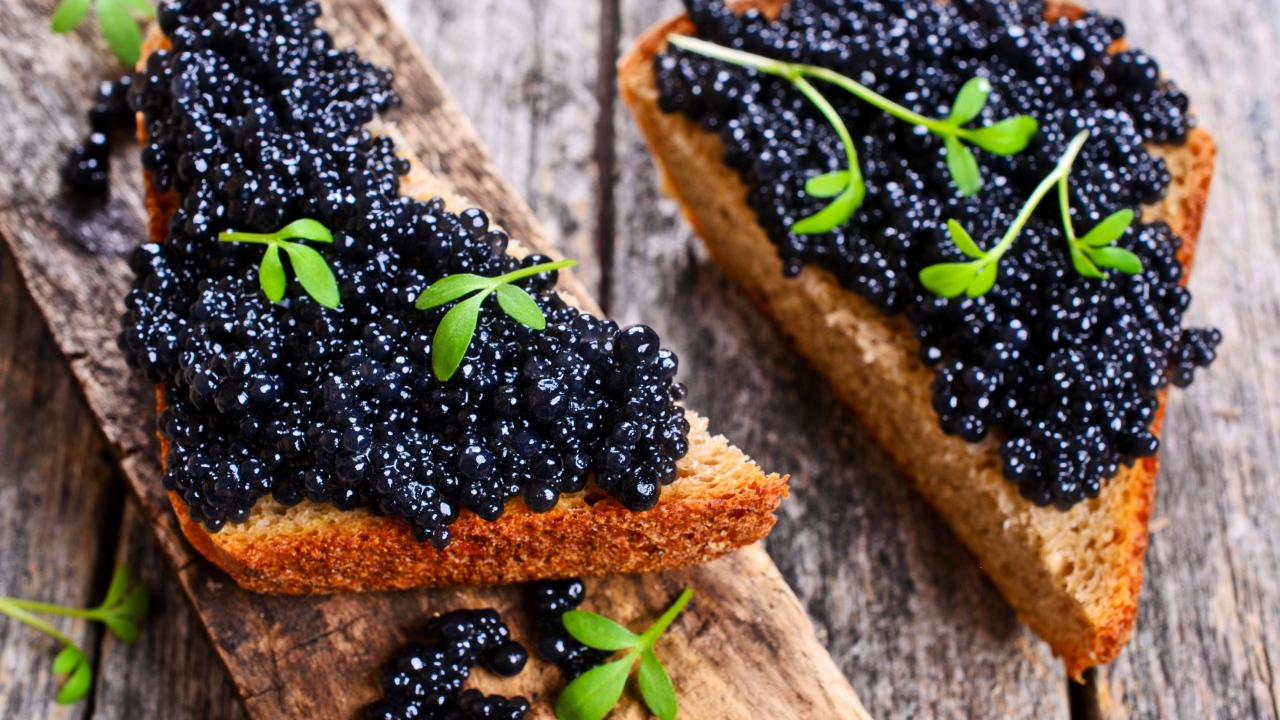 Два аппетитных бутерброда с черной икрой на деревянном столе