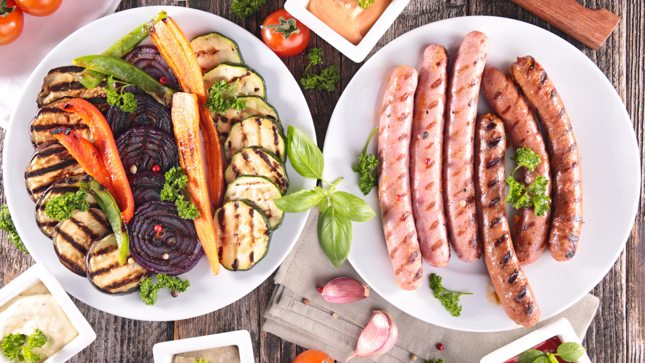 Овощи и сосиски гриль на столе с соусом