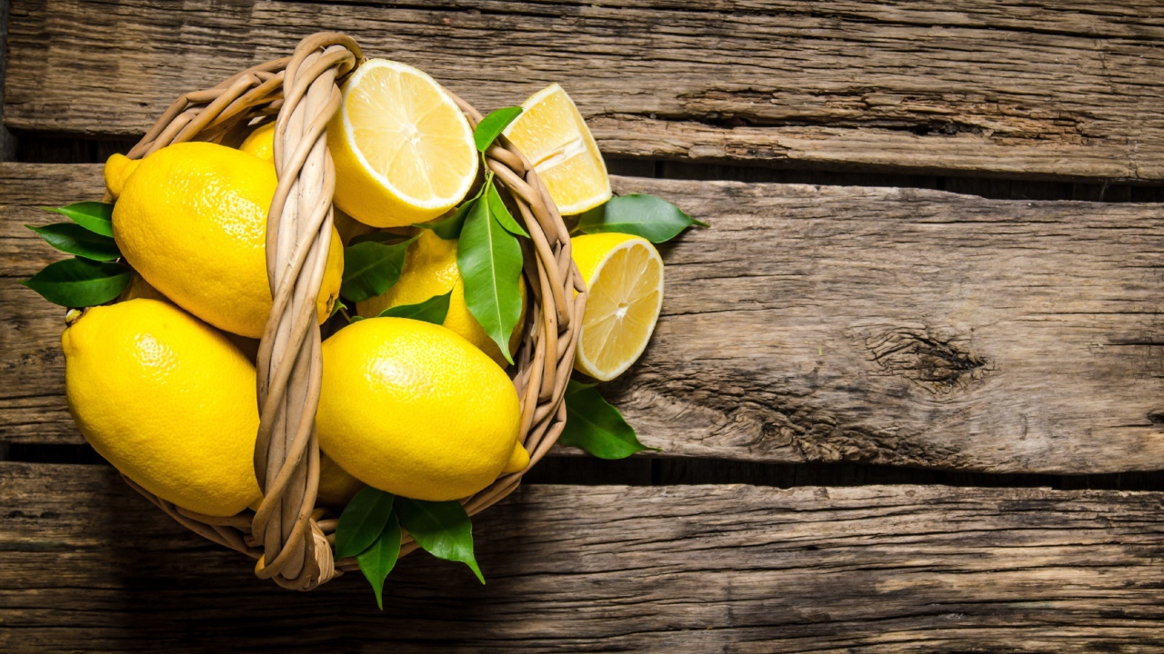 Красивые желтые лимоны в корзине на деревянном столе