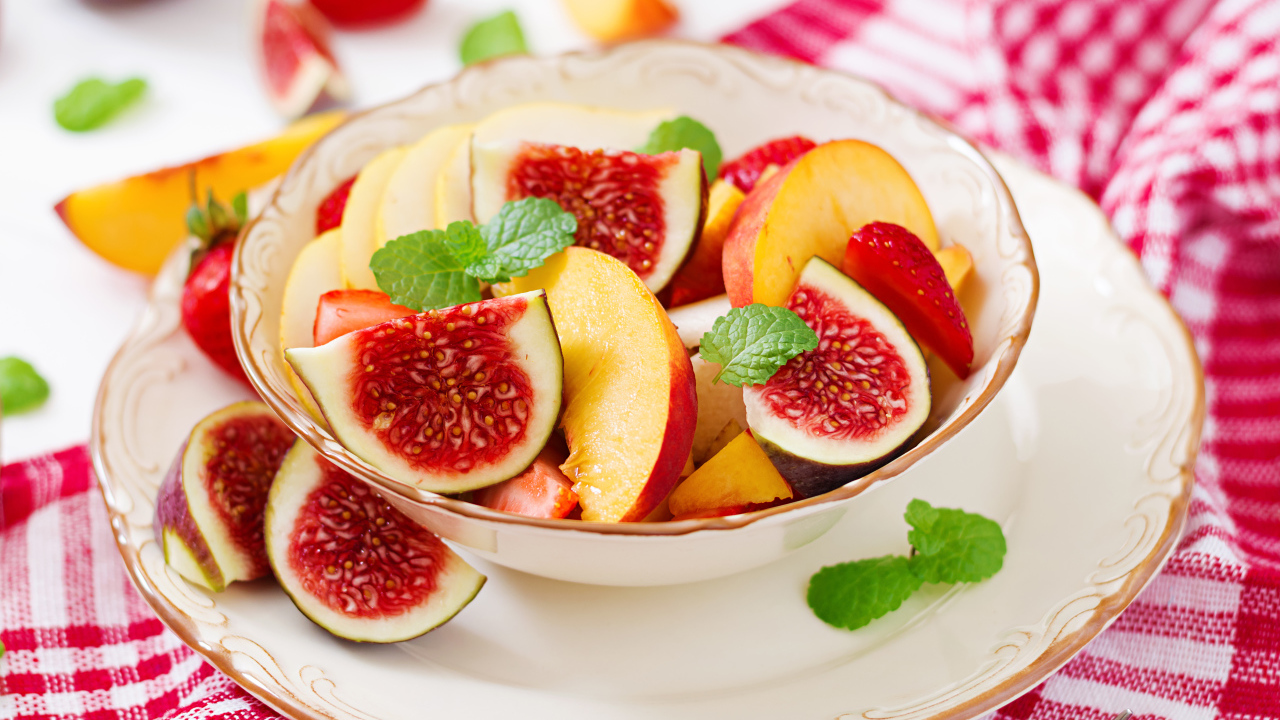 Свежие кусочки инжира и яблока в тарелке на столе