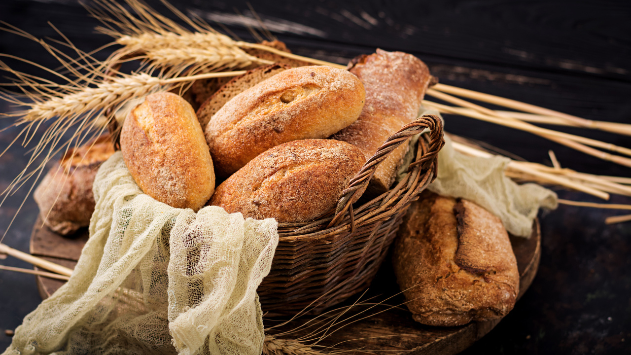 Свежая выпечка в корзине на столе с колосьями пшеницы