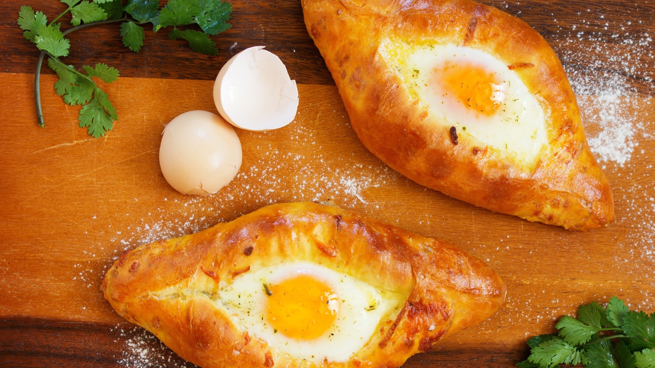 Две булки с яйцом, скорлупой и зеленью на столе