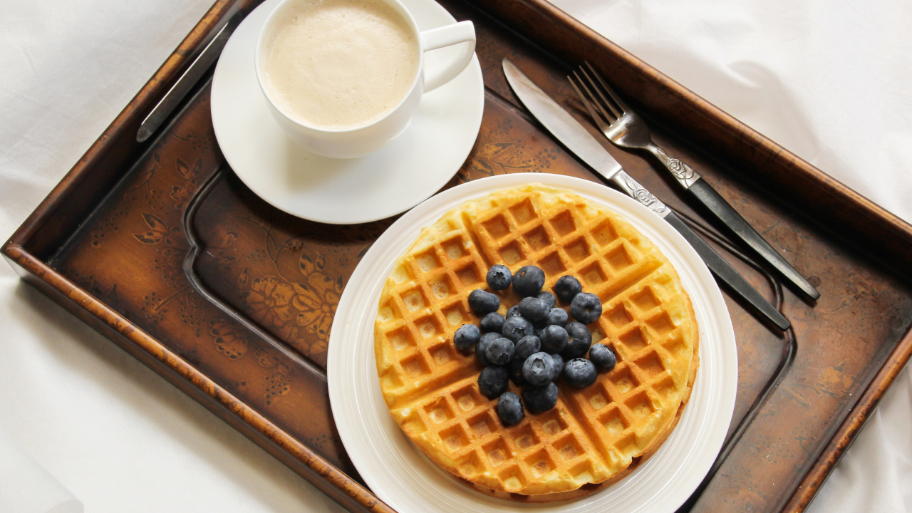 Чашка кофе и сладкие вафли с черникой на завтрак