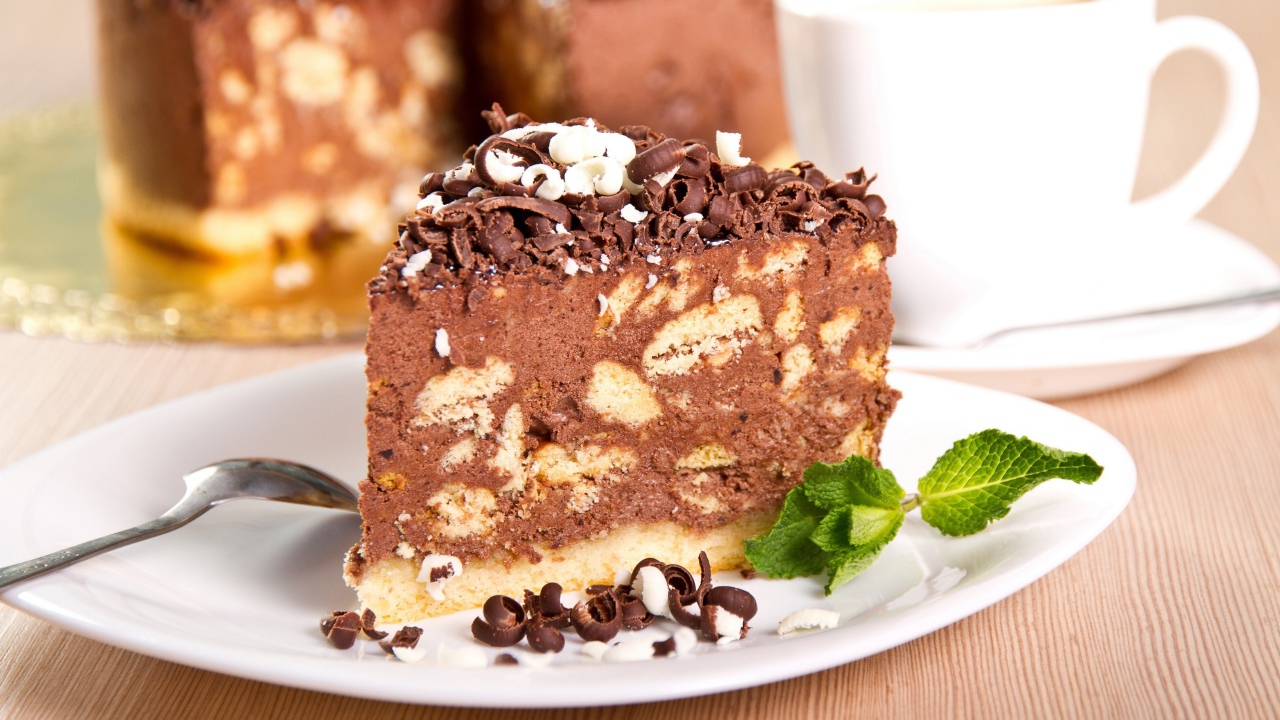 Кусок торта с шоколадом и листьями мяты на тарелке