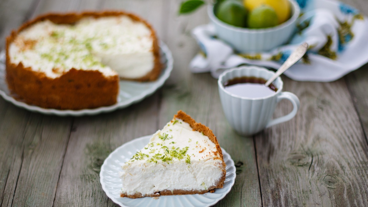 Кусок чизкейка на столе с чашкой чая