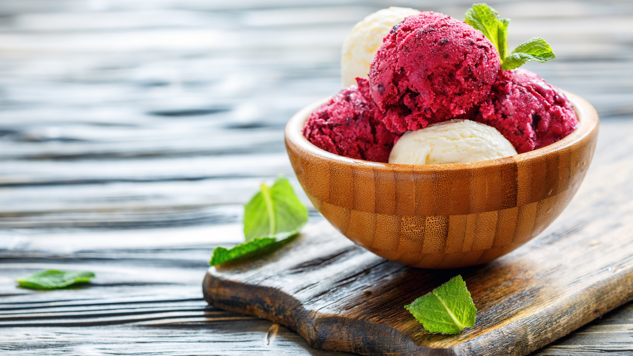 Шарики фруктового и ванильного мороженого в деревянной миске на столе