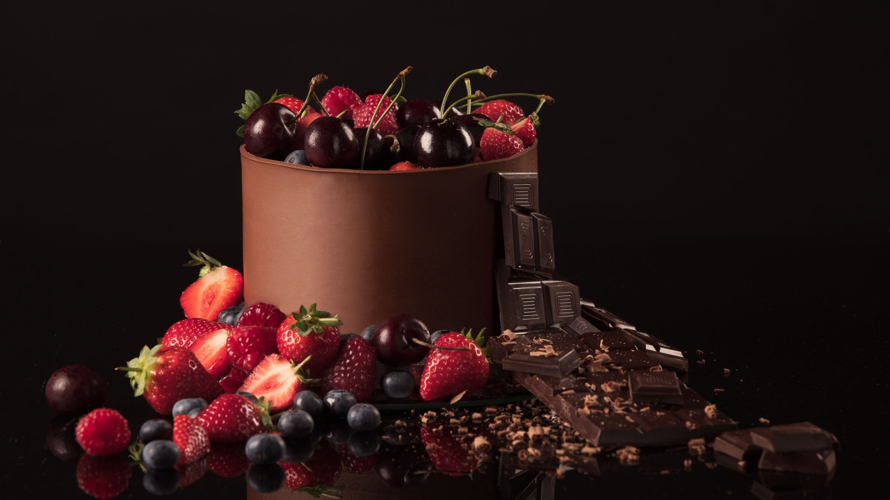 Черный шоколад с ягодами черники, малины, клубники и вишни на черном фоне