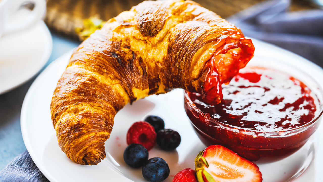 Круассан с джемом и ягодами на тарелке