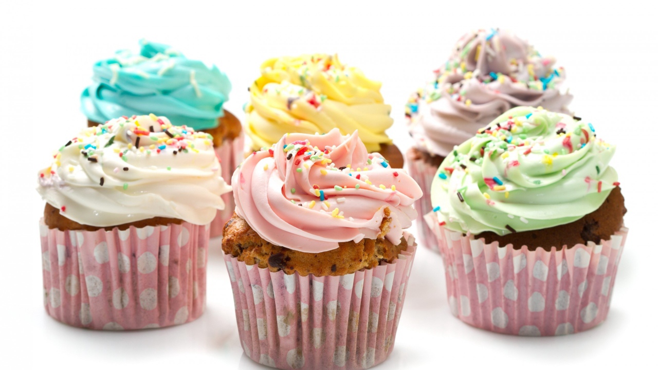 Кексы с разноцветным кремом на белом фоне