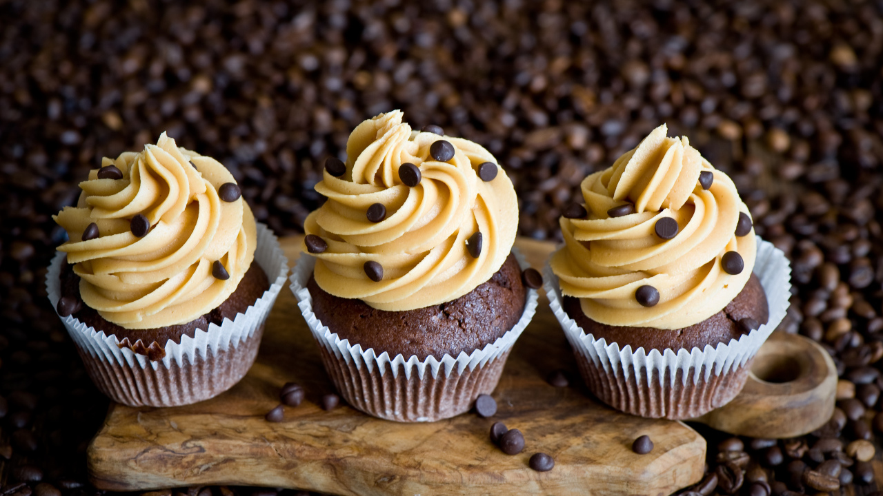 Кексы с кремом и зернами кофе на столе 