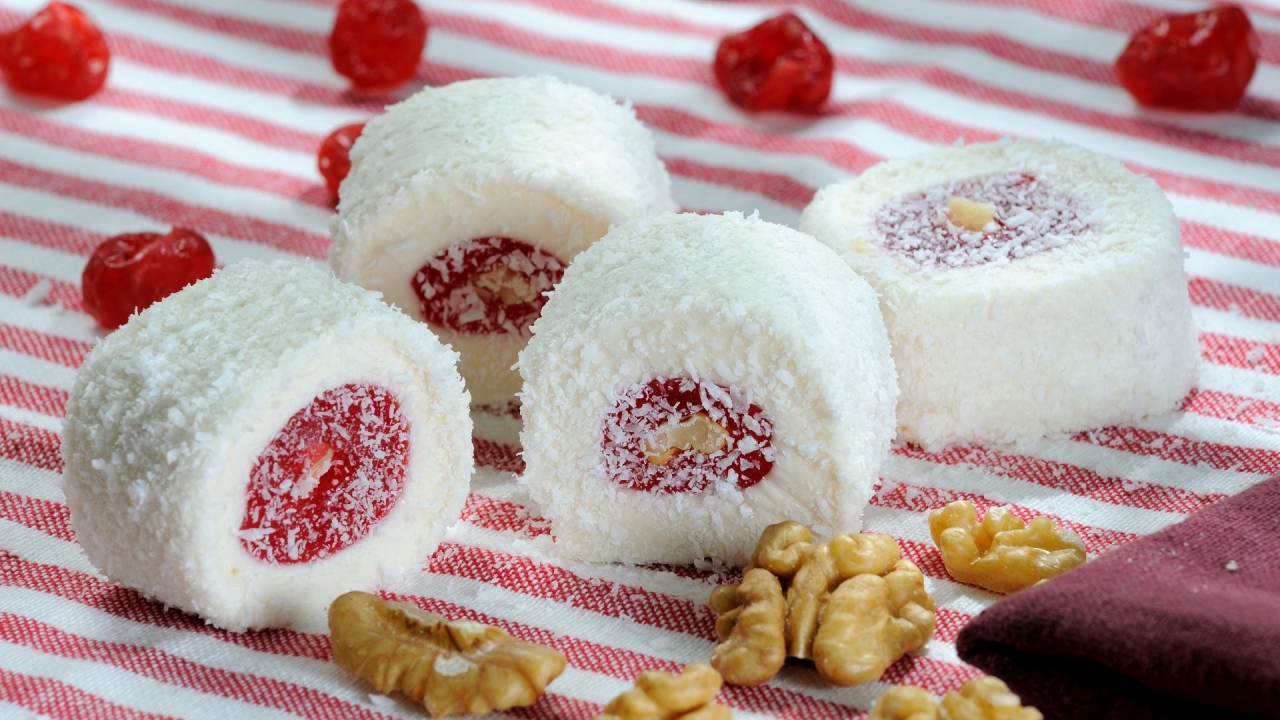 Десерт с джемом и кокосовой стружкой на столе с орехами