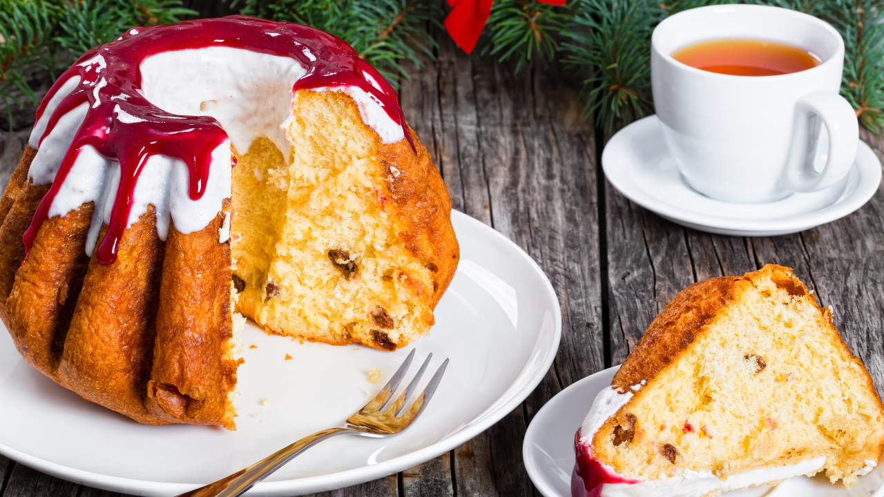 Праздничный кекс с глазурью на столе с чашкой чая