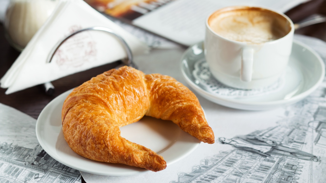 Свежий круассан и чашка кофе на завтрак 
