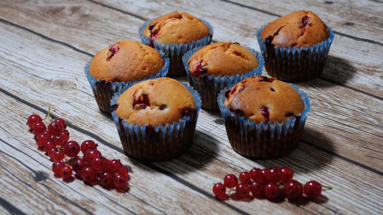 Свежие кексы с красной смородиной на деревянном столе 