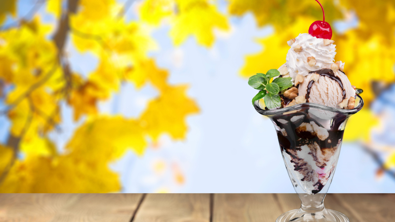 Мороженое в креманке с вишенкой на фоне желтых листьев