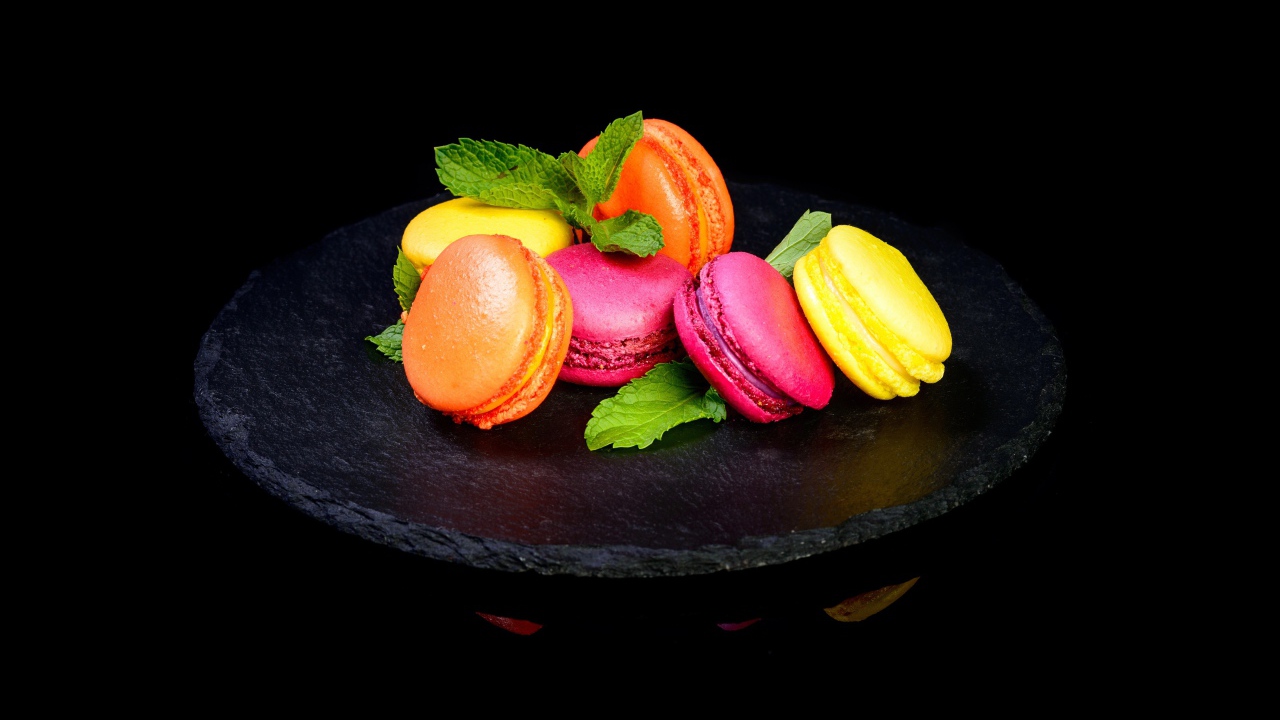 Разноцветный десерт макарон на черном фоне