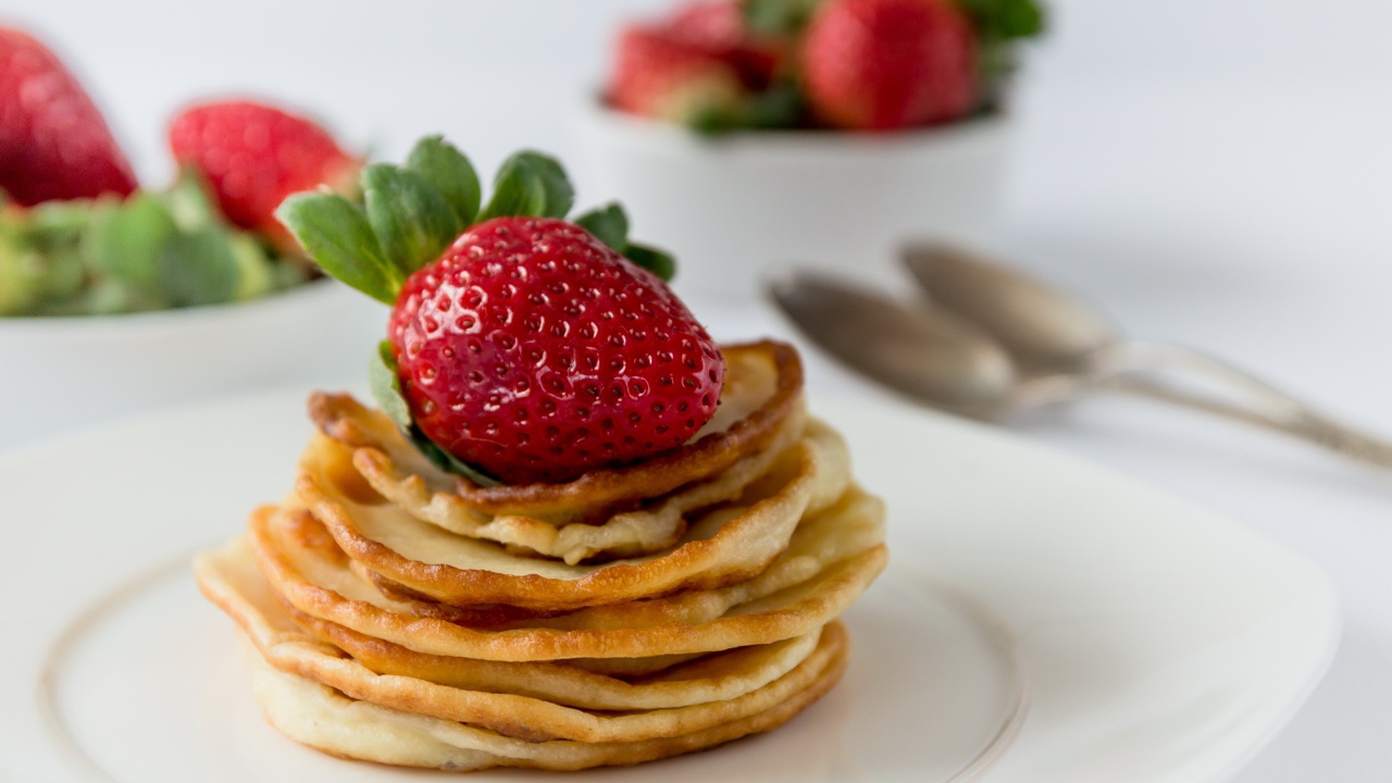 Оладьи с ягодами свежей клубники на белой тарелке 