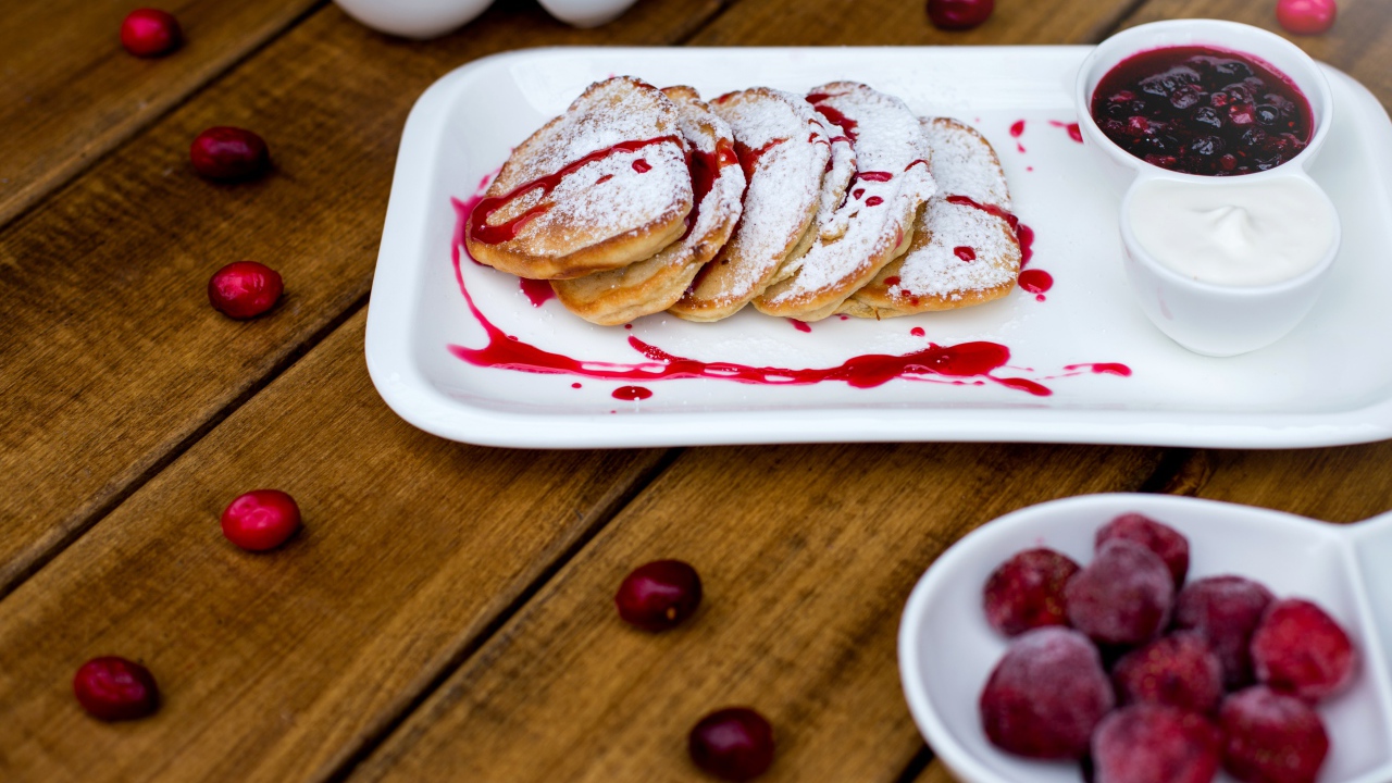 Оладьи с сахарной пудрой и вареньем на белой тарелке