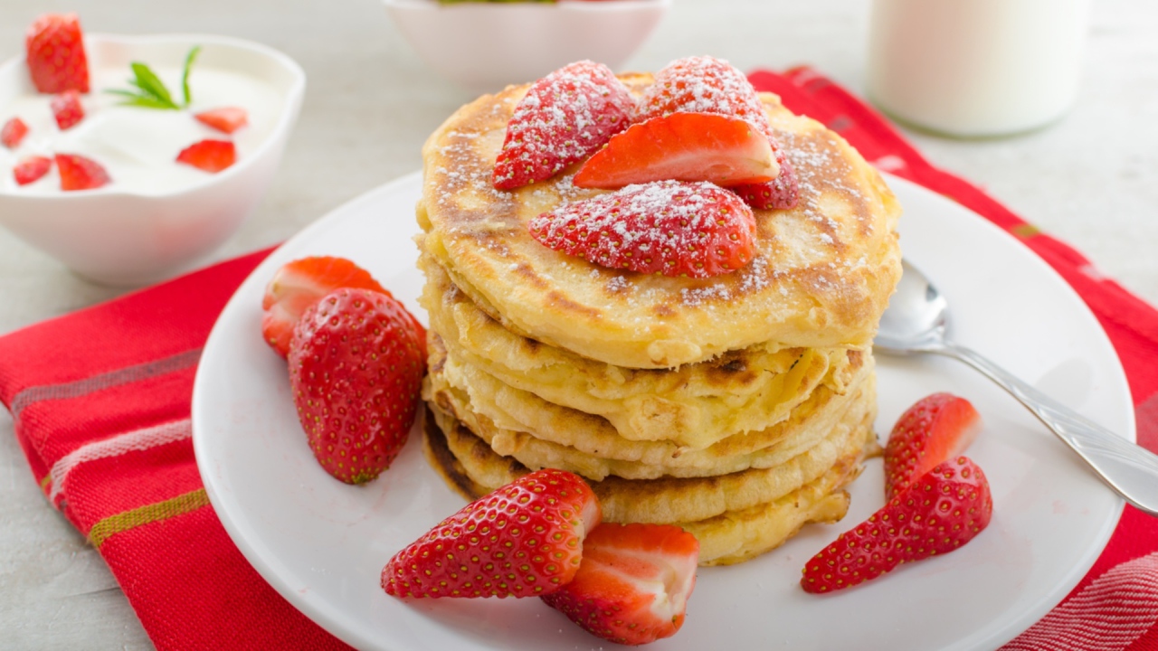 Оладьи с клубникой и сахарной пудрой на белой тарелке 