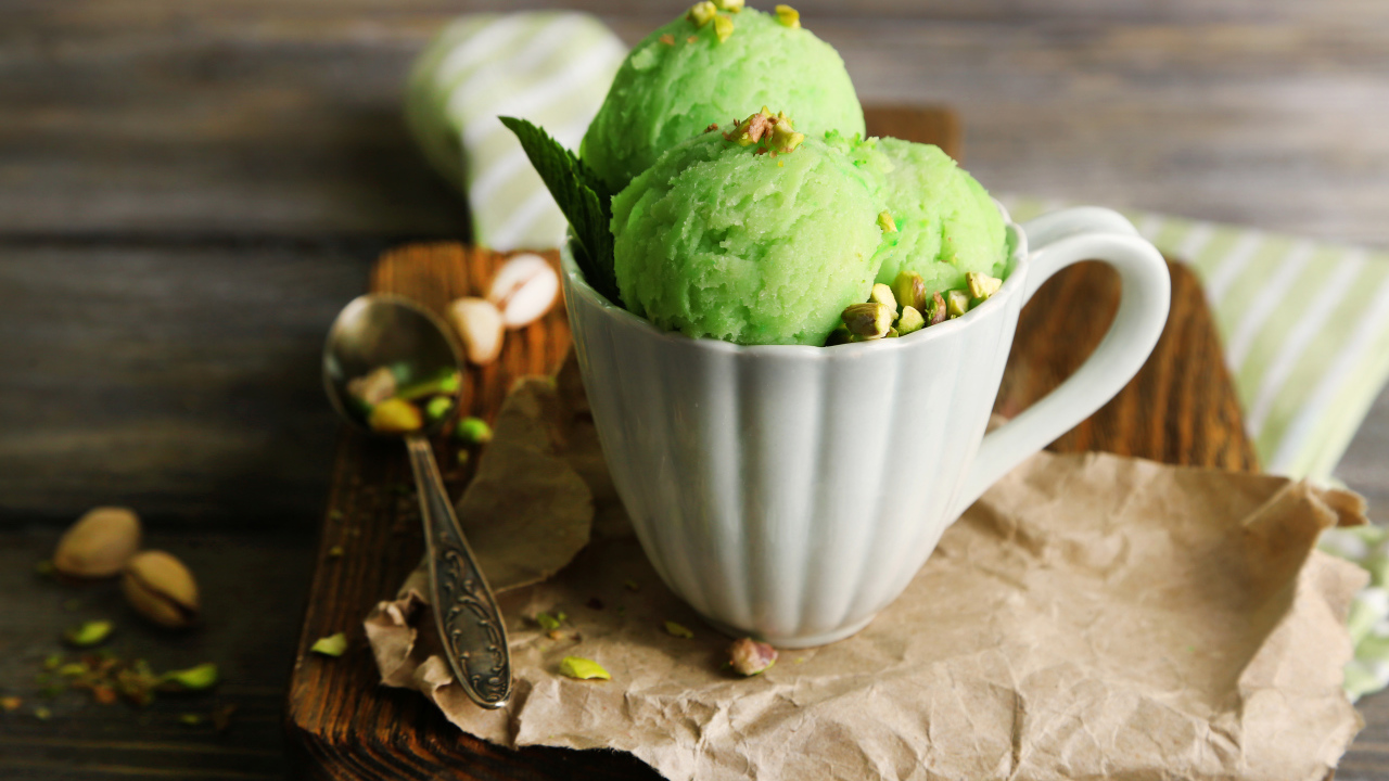 Фисташковое мороженое в белой чашке на столе
