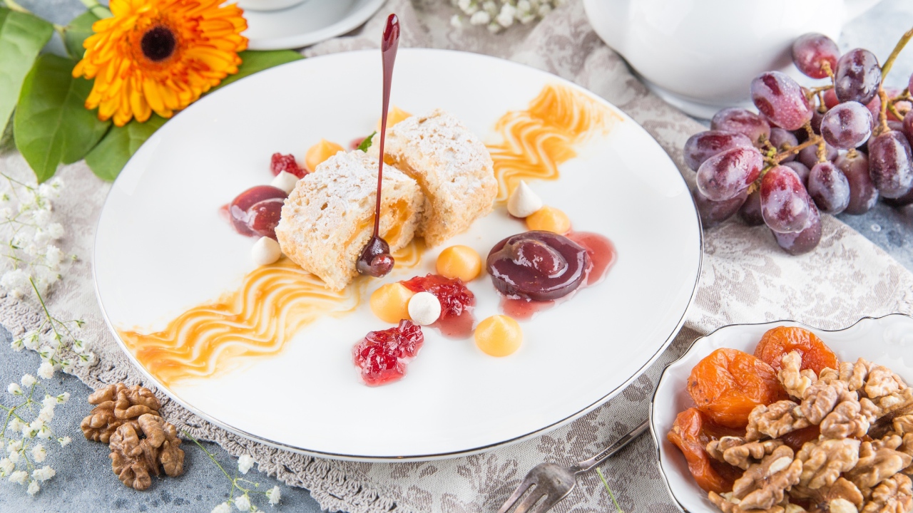 Сладкий рулет с сухофруктами и джемом на тарелке 