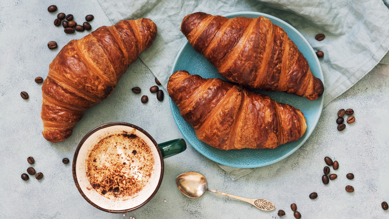 Три круассана на столе с чашкой кофе