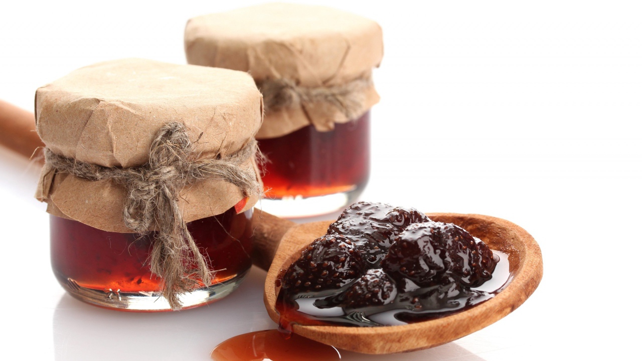 Две банки клубничного варенья на столе с ложкой 