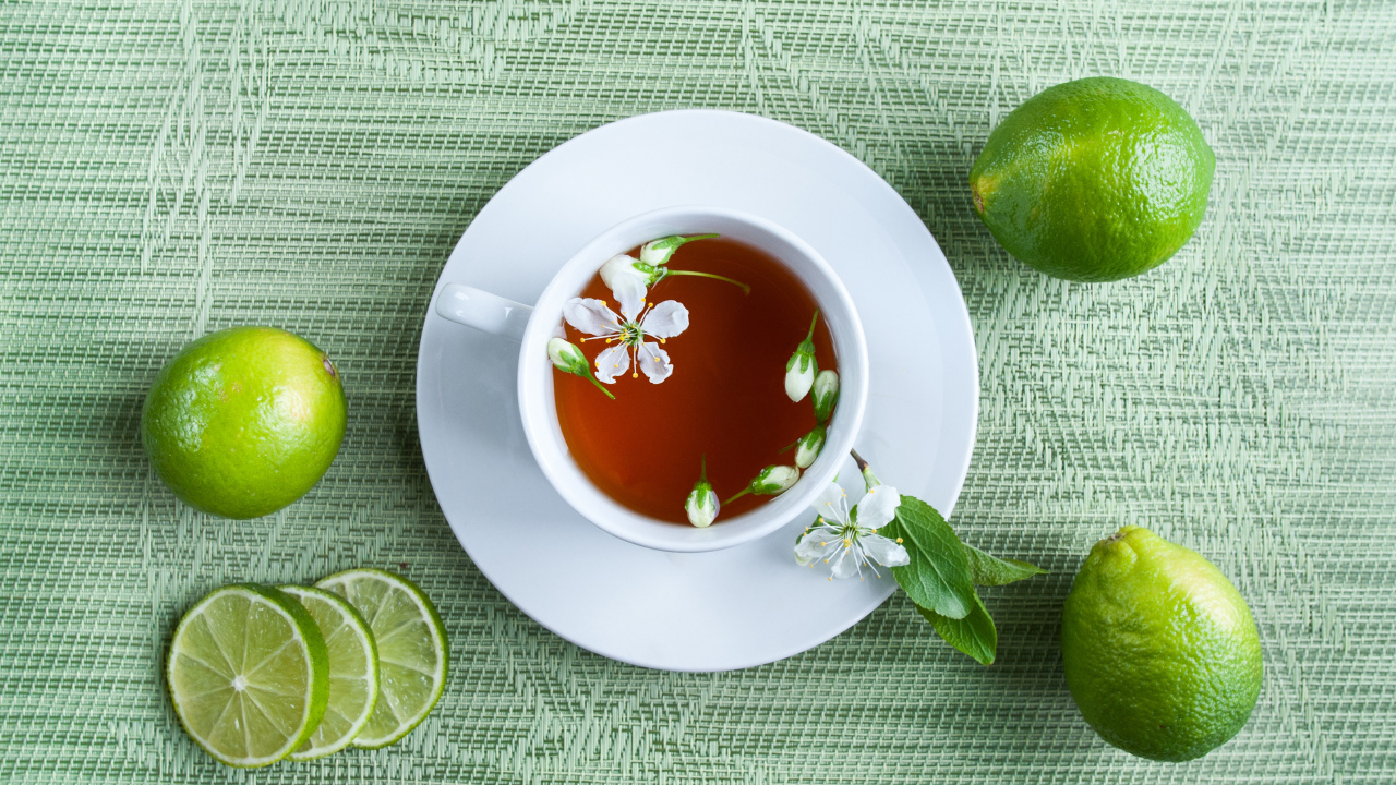 Чашка чая с зелеными лаймами на столе