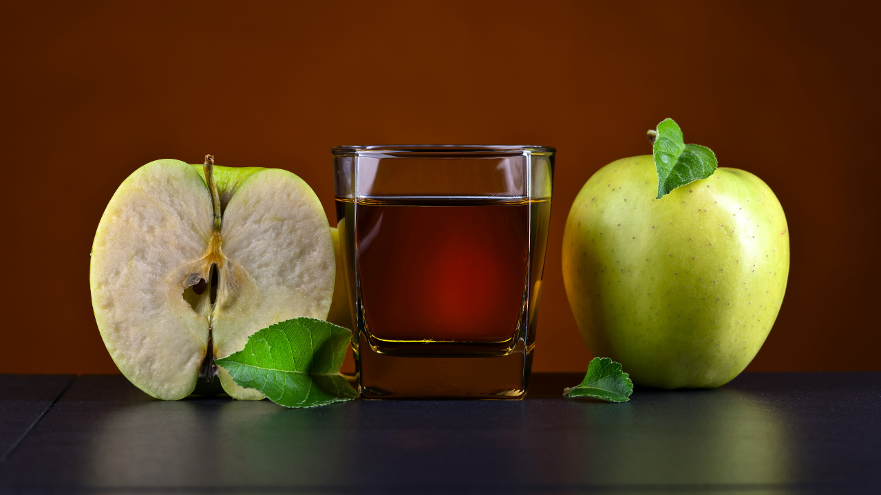 Стакан яблочного сока на столе с зелеными яблоками