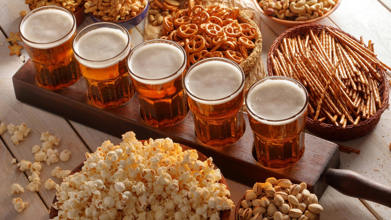 Пиво с орешками, фисташками, попкорном и печеньем на столе