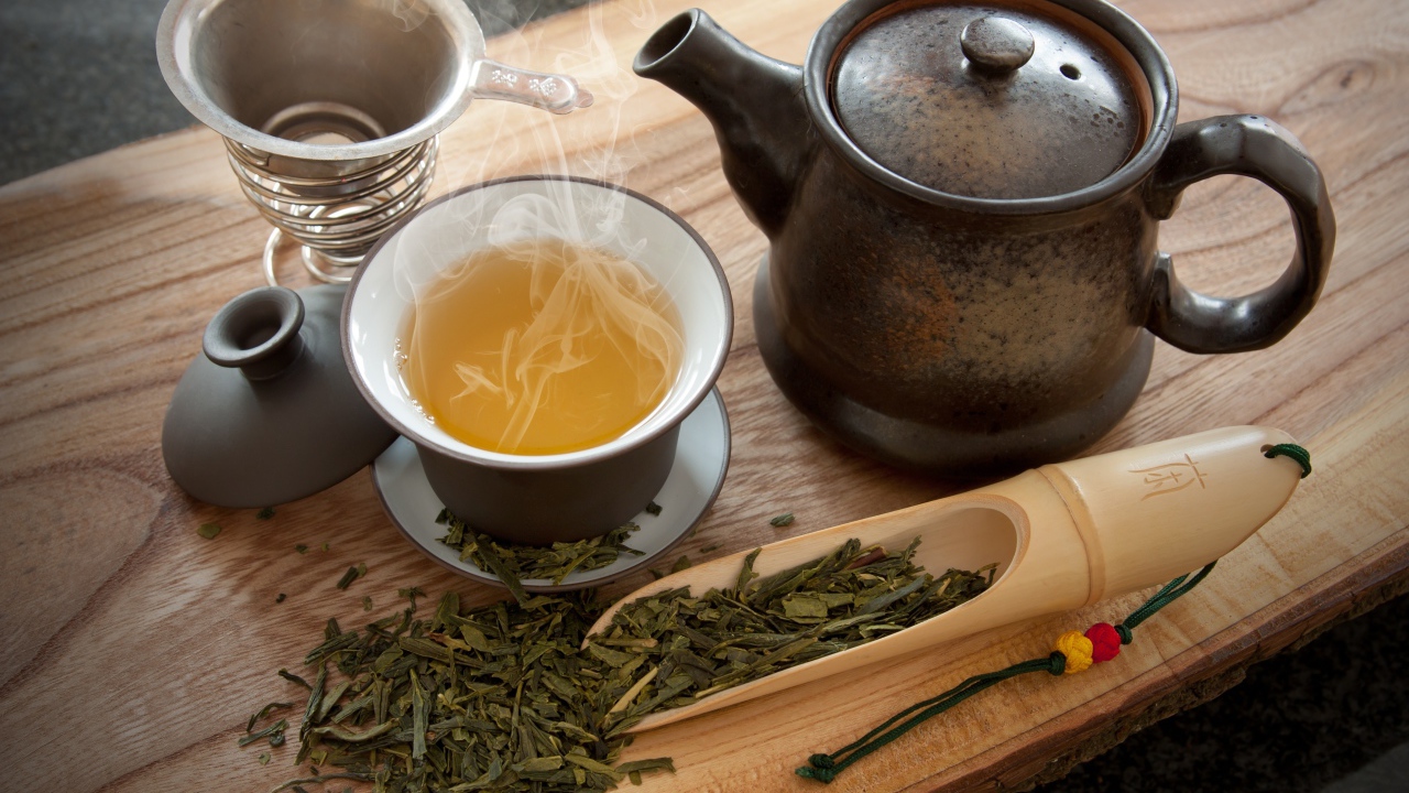 Свежий горячий чай на столе с чайными листьями и чайником