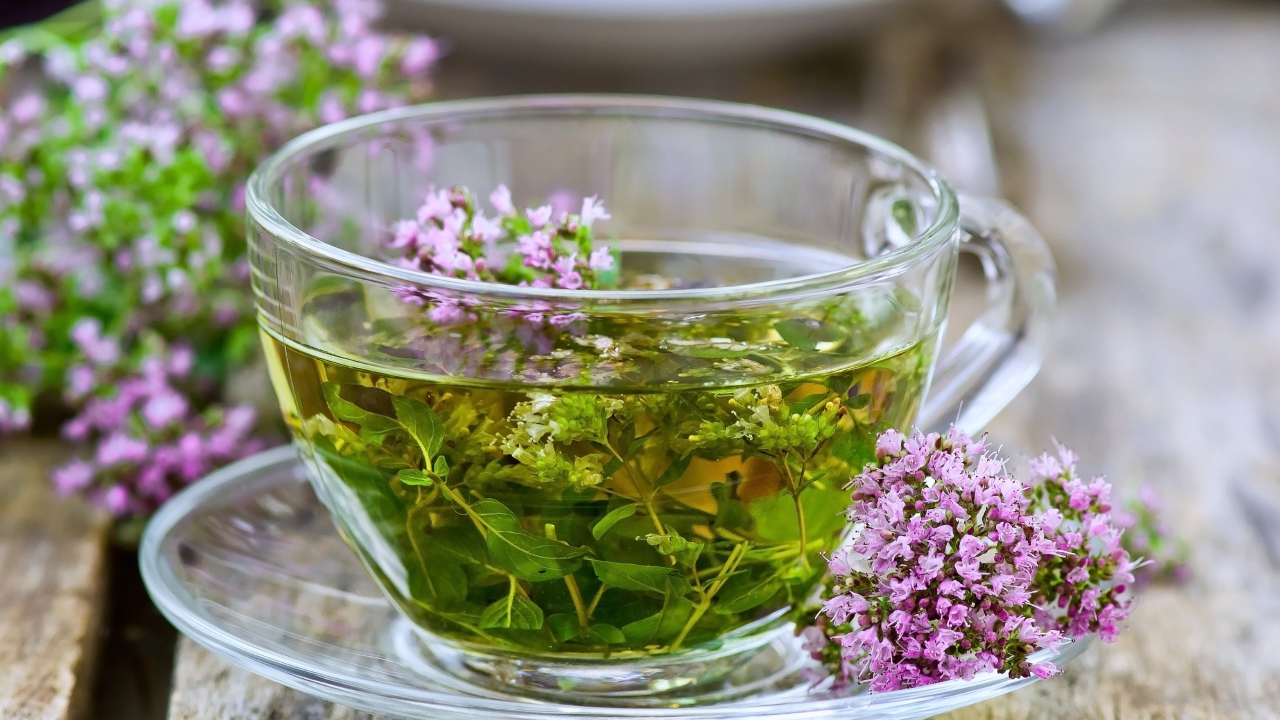 Стеклянная чашка зеленого чая с цветами чабреца