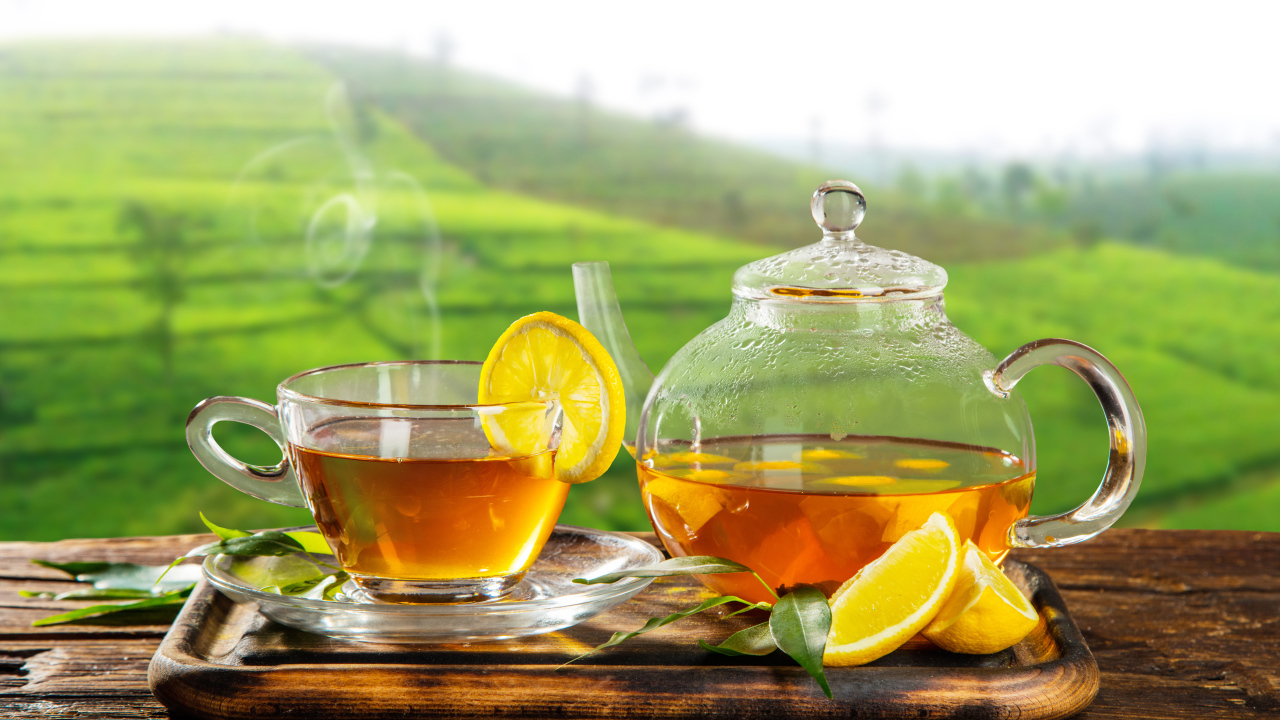 Зеленый чай с лимоном с стеклянной чашке на столе