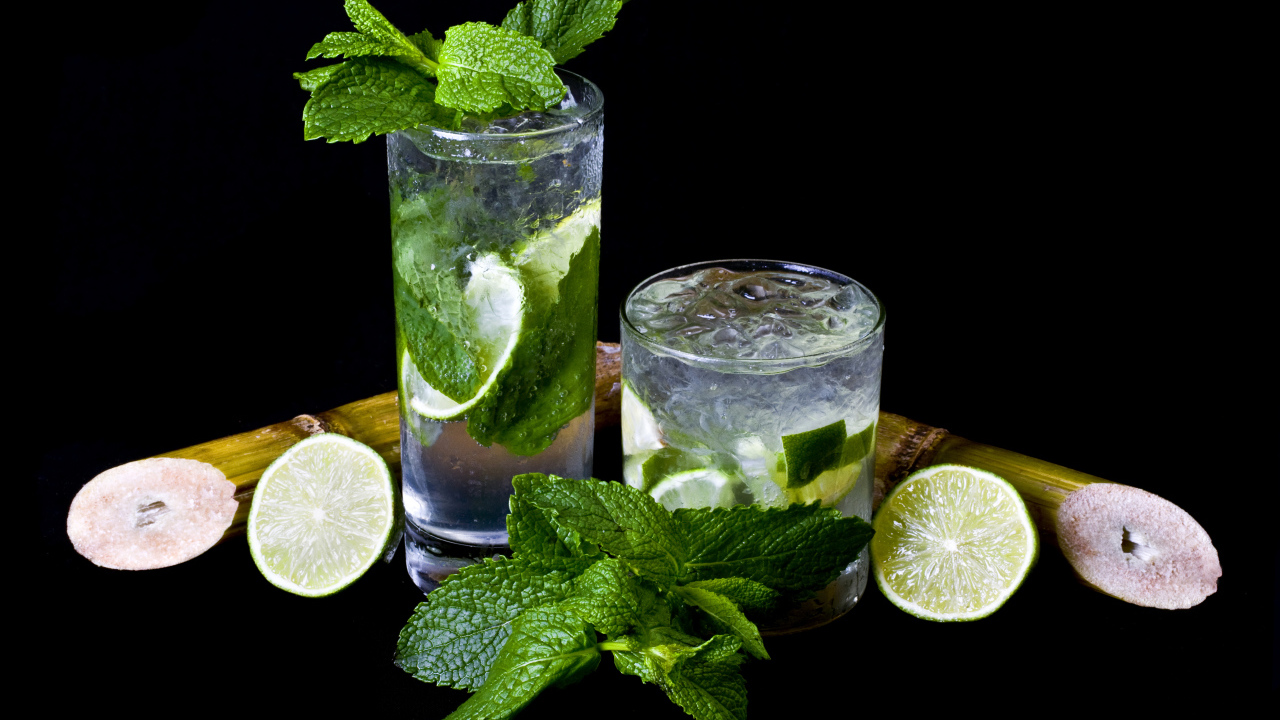 Напиток мохито в стаканах с лаймом и листьями мяты на черном фоне