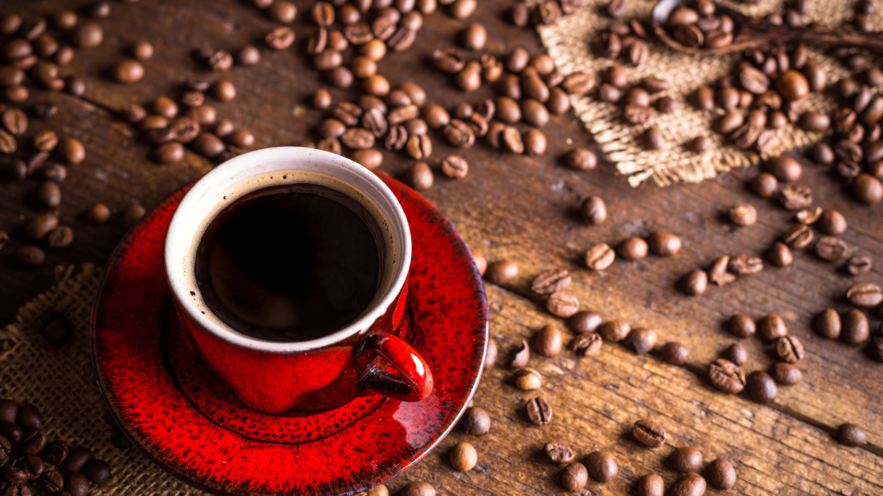 Красная чашка кофе на столе с зернами кофе