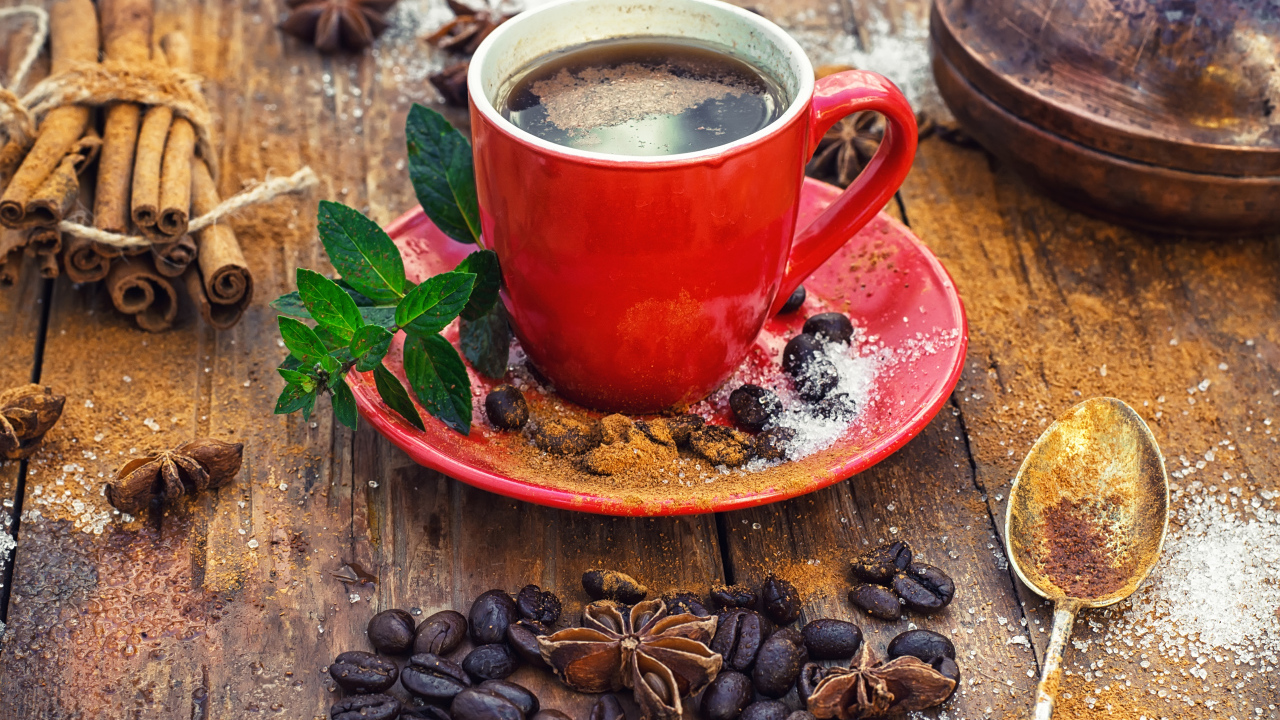 Красная чашка кофе на столе с зернами  и бадьяном и корицей