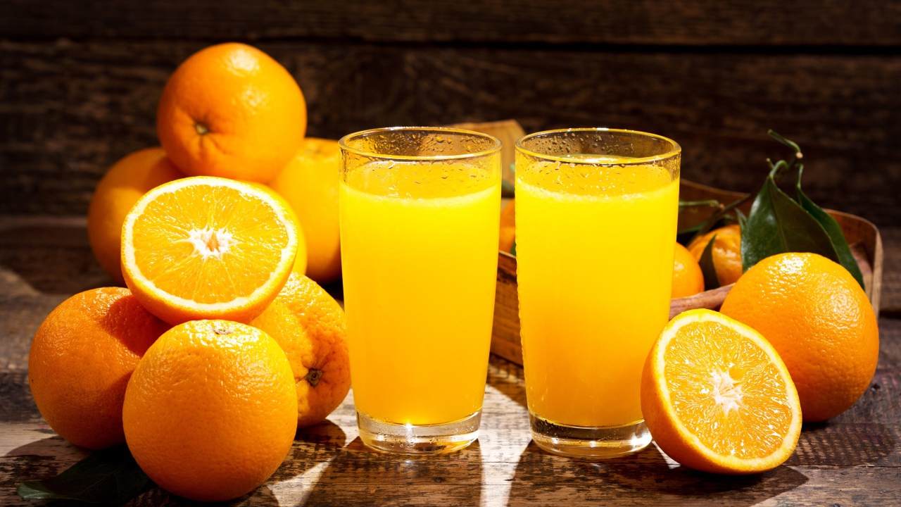 Два стакана свежего апельсинового сока на столе с фруктами