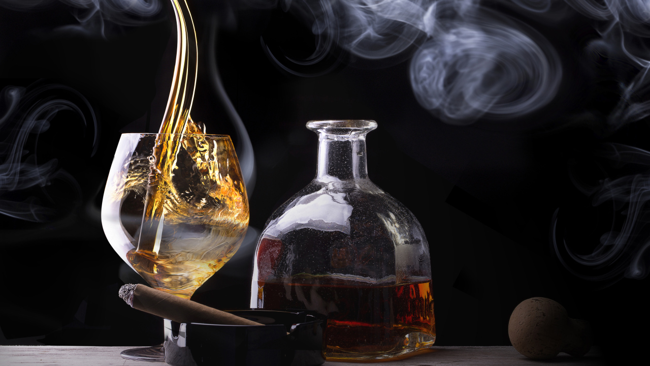 Виски в бокале на столе с бутылкой и сигарой 